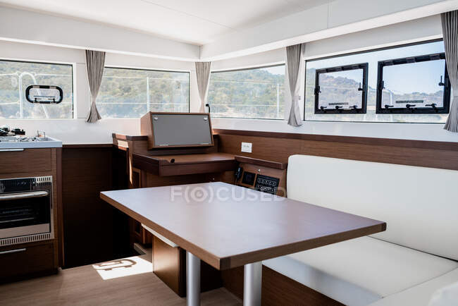 Interno di lusso di sala da pranzo con divano e tavolo in legno in cabina di catamarano contemporaneo — Foto stock