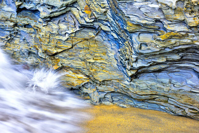 A paisagem marinha íntima de uma onda na areia dourada com um fundo de rocha, com uma textura bonita — Fotografia de Stock