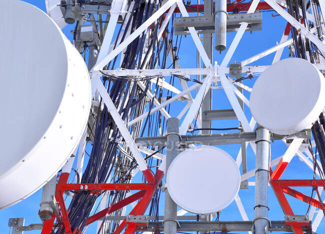 Low angle of modern radio tower with many round antennas located against blue sky — Stock Photo
