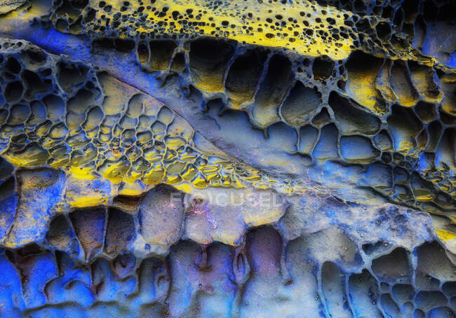 Крупный план абстрактный текстурированный фон из желтой и синей поверхности натурального материала, покрытого отверстиями — стоковое фото