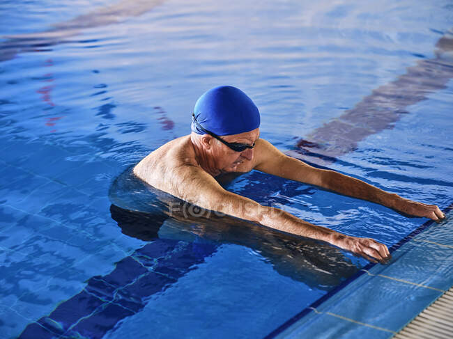 Зрілий чоловік у плавальній шапці стоїть у басейні під час уроку з гідробіології. — стокове фото