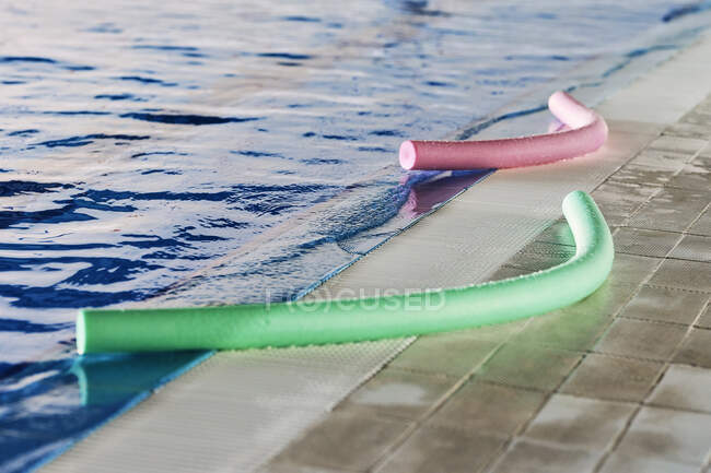 Локшина зеленого і рожевого пінопласту розміщена біля басейну для тренування водної аеробіки. — стокове фото
