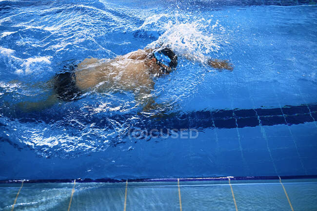 Високий кут підходить для чоловіків, які плавають у стилі повзун у басейні під час тренувань — стокове фото