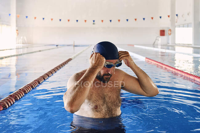 Schwimmer legt Schwimmbrille ab und macht Pause beim aktiven Training — Stockfoto