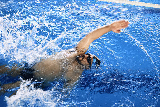 Haut angle de forme mâle nageant en rampant style dans la piscine pendant l'entraînement — Photo de stock