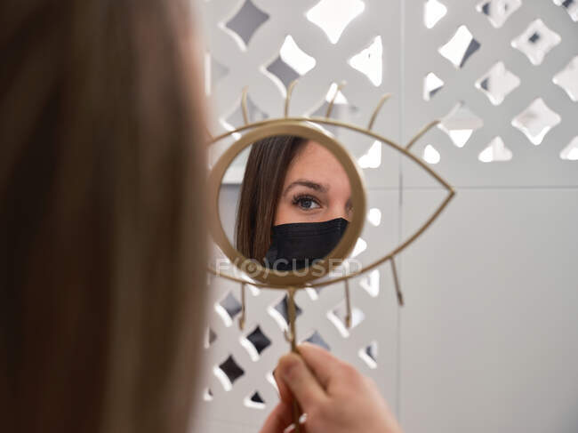 Spiegelbild einer zufriedenen jungen Kundin mit perfekten Wimpern und Augenbrauen nach einer Schönheitsbehandlung im professionellen Salon — Stockfoto