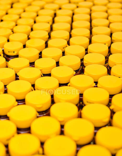Повний каркасний фон пляшок з жовтими ковпачками та рідкою медициною, розміщеними на конвеєрі в лабораторії фармацевтичного виробництва — стокове фото