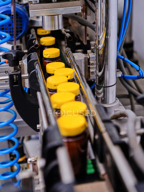 De cima da máquina farmacêutica moderna tampando garrafas plásticas com medicina líquida no transportador na fábrica — Fotografia de Stock