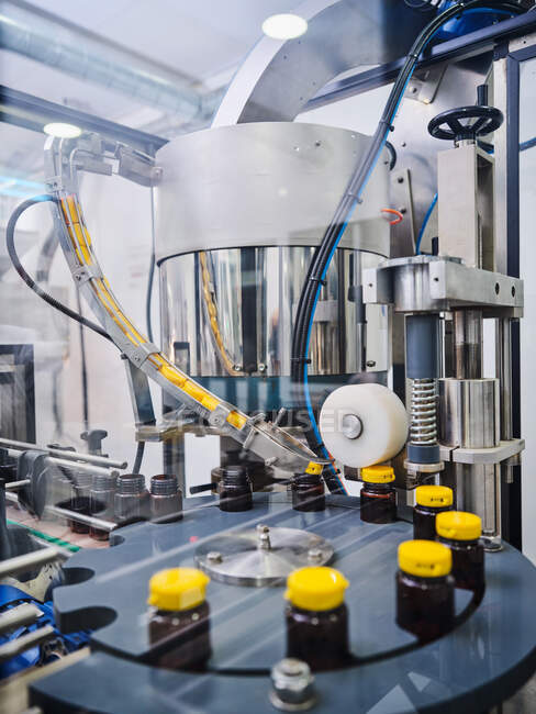 Полиэтиленовые бутылки с лекарством на конвейере шапочной машины в фармацевтической лаборатории — стоковое фото