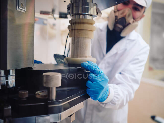 Чоловік, який працює в захисній одноманітній машині для начинки капсул на фармацевтичному заводі. — стокове фото