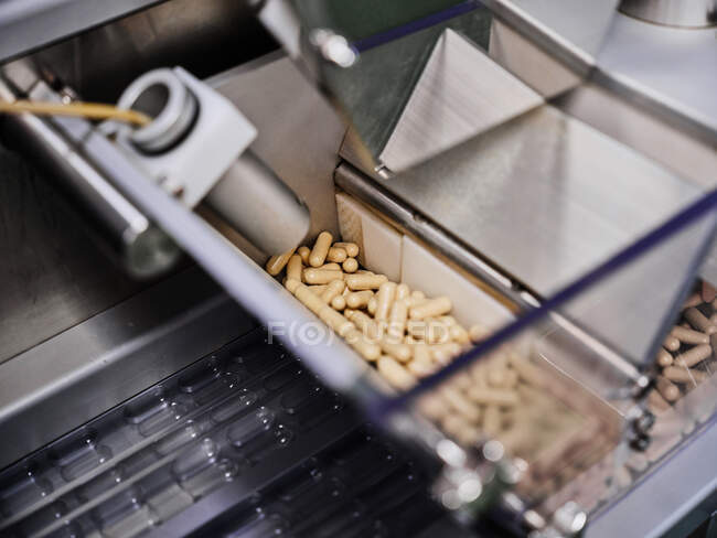 Macchina farmaceutica contemporanea con pile di pillole su trasportatore poste in laboratorio di produzione — Foto stock