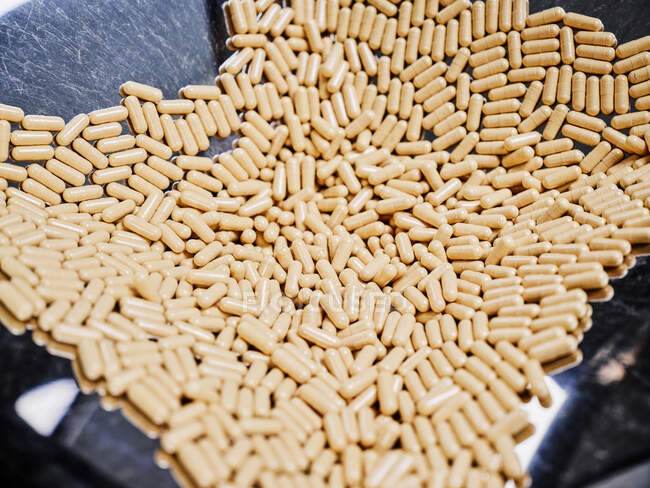 Dall'alto di pila di pillole di capsula messe su vassoio di metallo di macchina farmaceutica a fabbrica manifatturiera — Foto stock
