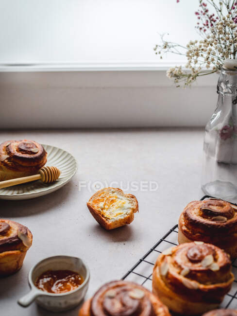 Panini di cannella deliziosi interi e dimezzati messi sul tavolo al mattino a casa — Foto stock