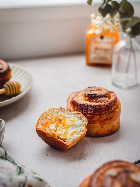 Petits pains à la cannelle entiers et coupés en deux placés sur la table le matin à la maison — Photo de stock