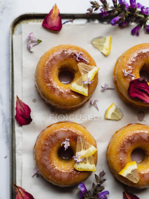 Vista superior de saborosos donuts no rack de refrigeração com folhas entre raminhos de lavanda florescendo na superfície de mármore — Fotografia de Stock