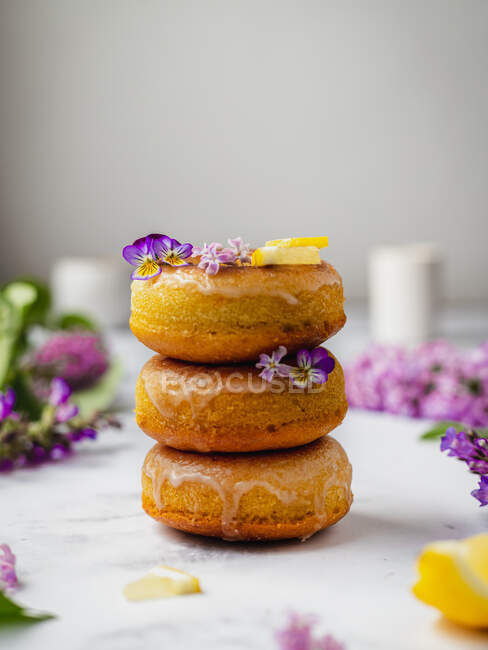 Haufen leckerer Donuts mit frischen Zitronenstücken und blühenden Lavandula-Blüten auf süßer Glasur — Stockfoto