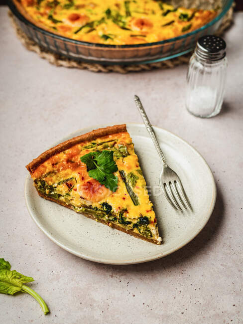Top view of yummy quiche slice with fresh parsley and asparagus placed on table — Stock Photo