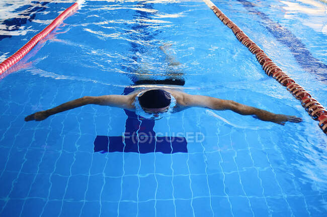 Высокий угол подтянутого мужчины плавание в вольном стиле в бассейне во время тренировки — стоковое фото
