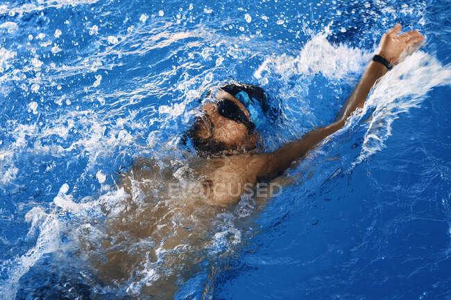 High angle of fit male swimming in crawl style in pool during training — Stock Photo
