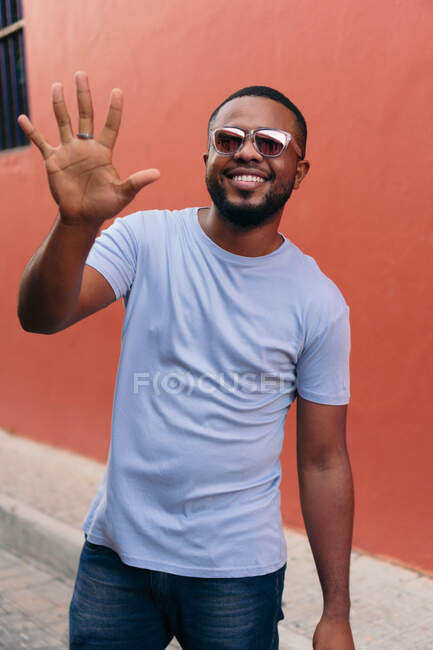 Улыбающийся человек показывает свою руку, гуляя на открытом воздухе — стоковое фото