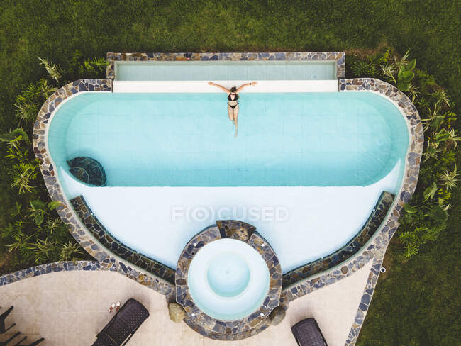 Vista dall'alto donna da sola in una piscina godendo di una giornata estiva soleggiata — Foto stock