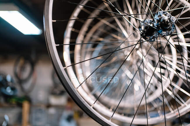 Desde abajo de metal brillante llantas de bicicleta colgando en rack en servicio de reparación - foto de stock