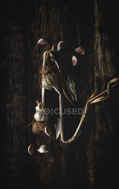 Сверху букет свежего фиолетового чеснока гвоздики помещены на темном деревянном фоне — стоковое фото