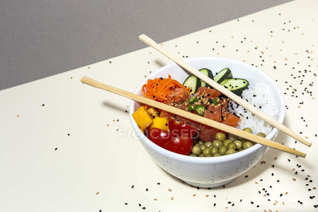 Сверху бамбуковые палочки для еды помещены поверх миски с вкусным блюдом из тыквы на столе, покрытом семенами кунжута — стоковое фото