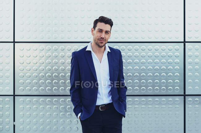 Self assured male entrepreneur in formal wear with hands in pockets looking at camera — Stock Photo