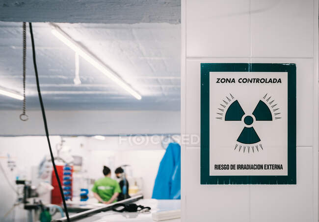 Signes avertisseurs de danger zone radioactive suspendue au mur près de l'entrée du laboratoire de rayons X dans une clinique vétérinaire avec des personnes travaillant à l'intérieur — Photo de stock