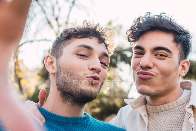 Positive gay couple taking self portrait and having fun in park at weekend — Stock Photo