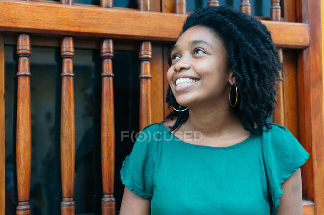 Mulher afro-americana bonita e alegre de bom humor em pé na rua da cidade. Mulher muito jovem fora com sorriso no rosto, conceito de emoções. — Fotografia de Stock