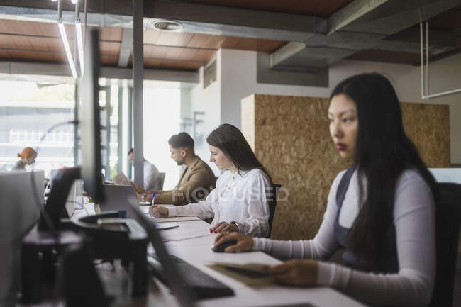 Gruppe fokussierter multiethnischer Kollegen sitzt am Tisch und arbeitet an einem Projekt im modernen Coworking Space — Stockfoto