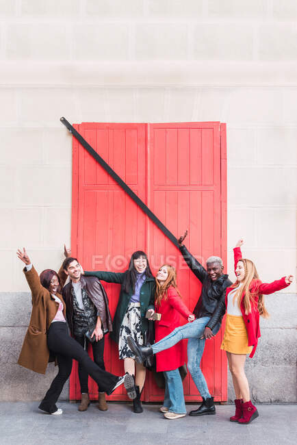 Група схвильованих багаторасових друзів розважаються в місті, стоячи на вулиці з піднятими руками — стокове фото