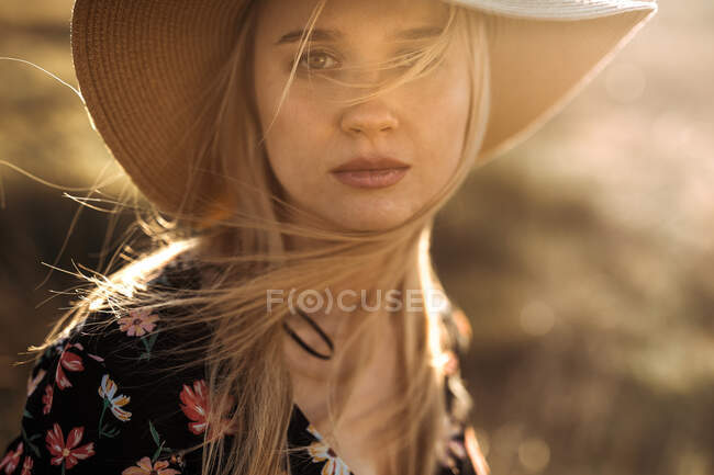 Retrato de una hermosa joven con sombrero en el campo mirando a la cámara - foto de stock