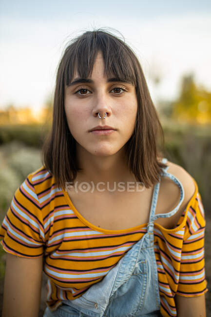 Caucasian young woman with nose piercing looking serious at camera — Stock Photo