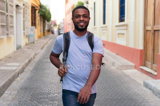 Homme noir portant un sac à dos tout en marchant en ville — Photo de stock