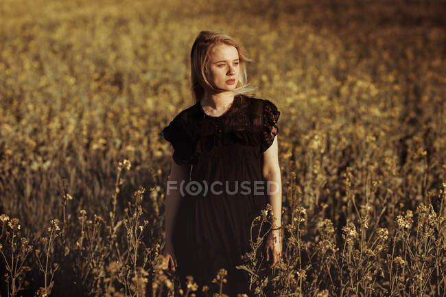 Портрет красивой молодой женщины в сельской местности, смотрящей вдаль среди цветов — стоковое фото