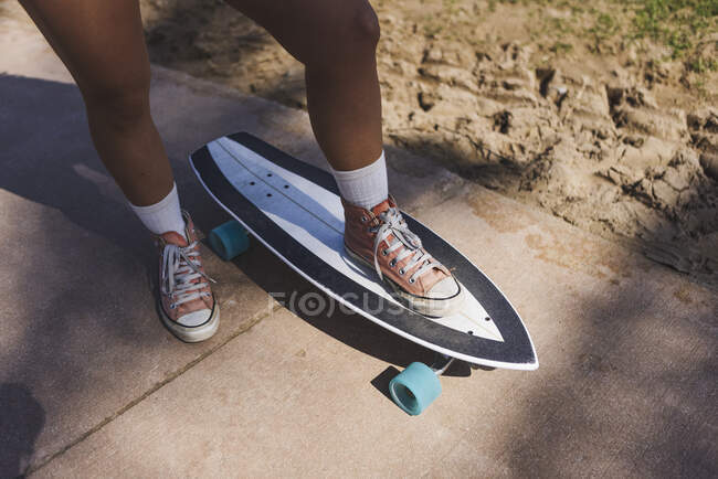 From above of unrecognizable sportive female in white socks and sneakers standing on skateboard on sidewalk during training in city — Stock Photo