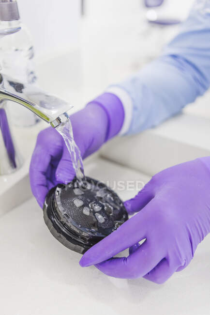 Hoher Winkel der Pflanzenfasern Zahnarzt wäscht Furniere mit sauberem Wasser in Spüle in Zahnklinik — Stockfoto