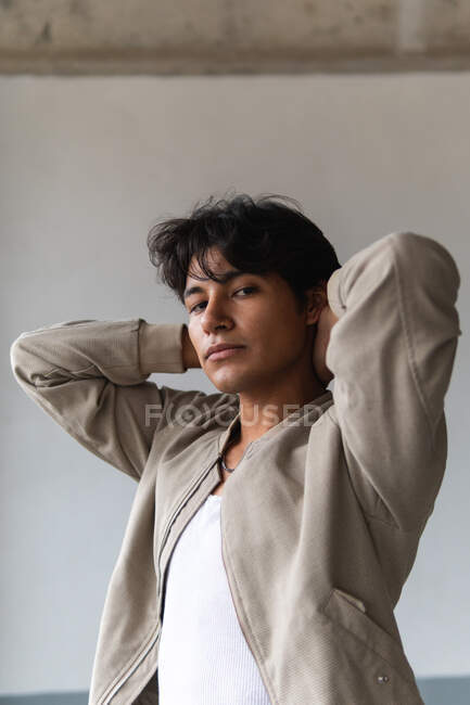 Portrait of young latin man looking confidently at camera with hands on neck against neutral background — Stock Photo