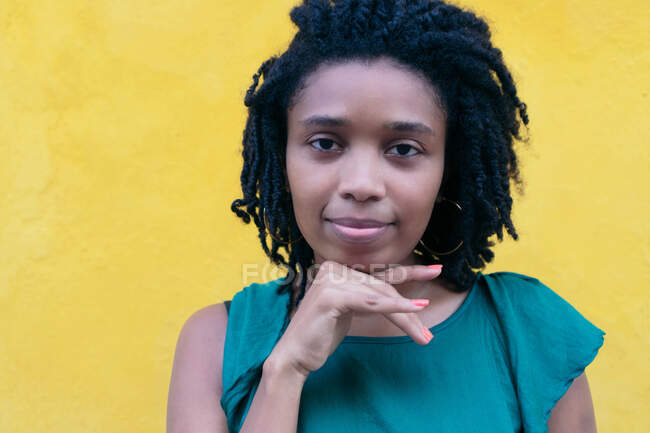 Portrait de jeune femme africaine à la coiffure afro appuyée sur un mur — Photo de stock