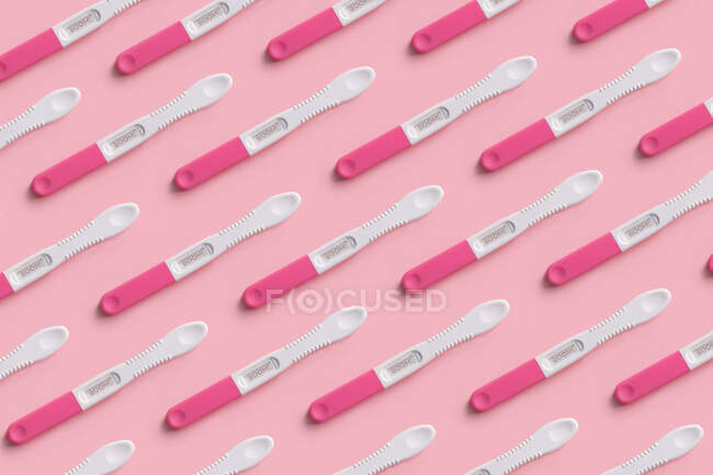 Вид сверху на коллаж теста на беременность, размещенный четными рядами на розовом фоне — стоковое фото