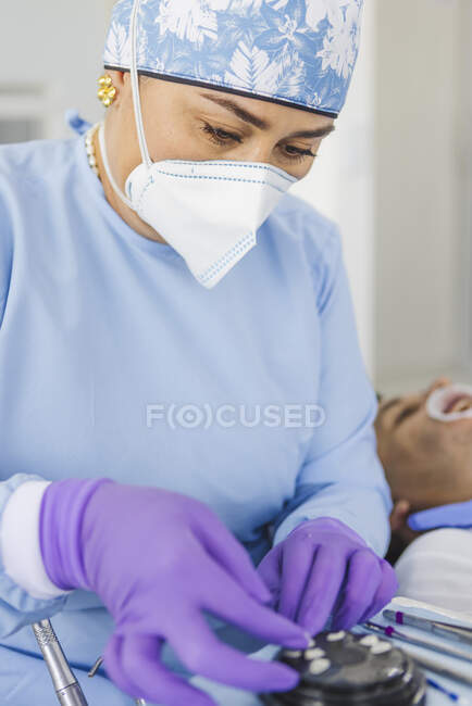 Жінка-стоматолог з інструментом підготовки вінірів до процедури в клініці — стокове фото