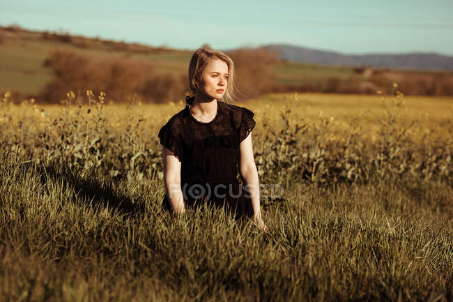 Portrait of a beautiful young woman with in countryside looking away among flowers — Stock Photo