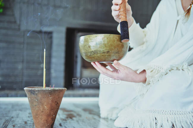 Mujer de las cosechas jugando tazón de canto con el delantero de madera durante la práctica espiritual - foto de stock