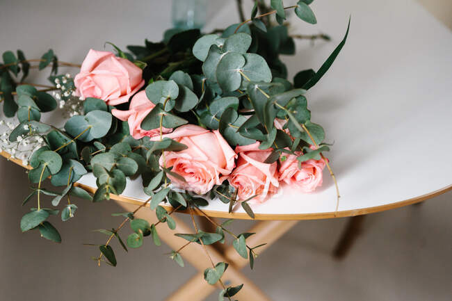 From above pink roses bouquet with green leaves lying on table — Stock Photo
