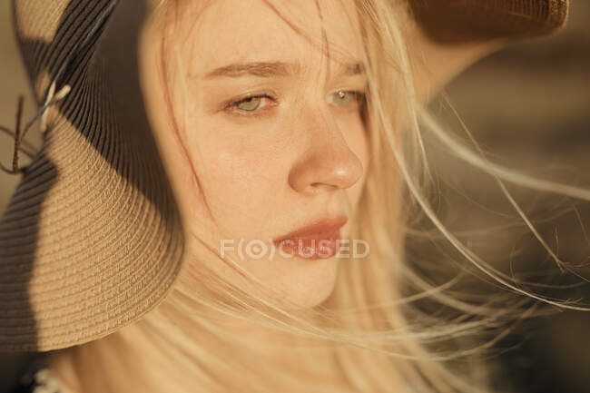 Retrato de uma bela jovem mulher com chapéu no campo olhando para longe — Fotografia de Stock