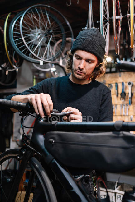 Schwerwiegender männlicher Mechaniker fixiert Lenker des Fahrrads während Arbeit in Reparaturwerkstatt — Stockfoto