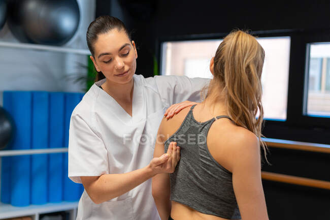 Osteópata hembra hombro apropiado unirse a la paciente en el dolor durante la sesión de fisioterapia - foto de stock